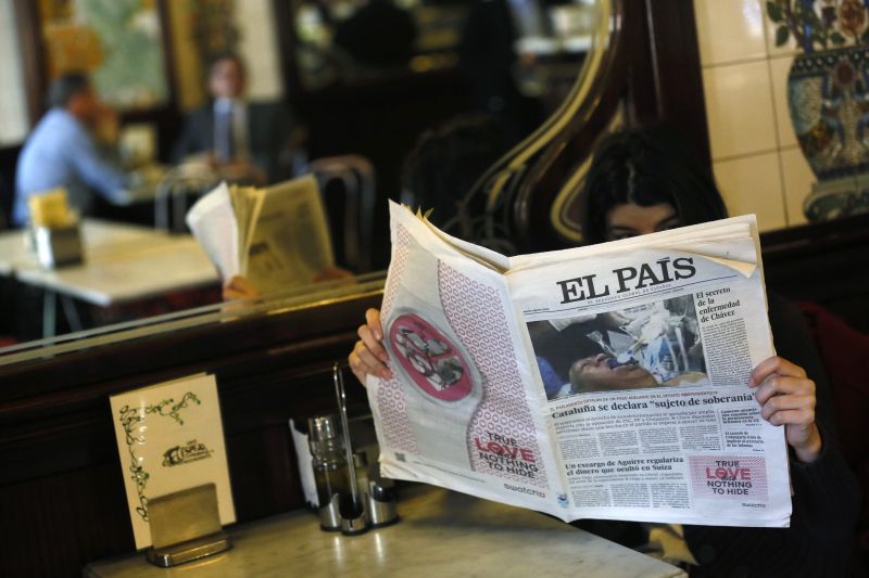 Mulher lê exemplar do jornal espanhol El País com imagem falsa do presidente venezuelano Hugo Chávez na primeira página | Andrea Comas/Reuters