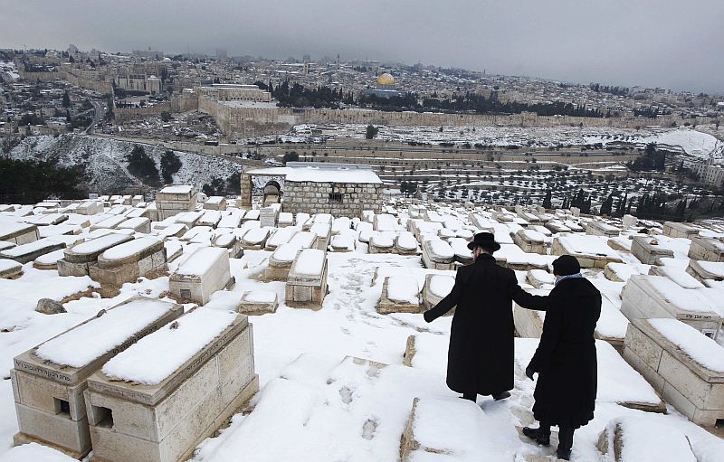 Judeus ultra-ortodoxos caminham sobre a neve em um cemitério no Monte das Oliveiras, em Jerusalém: onda de frio atinge a região | REUTERS/Baz Ratner