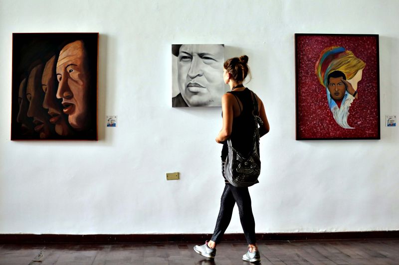 Visitante observa retratos de Chávez, em Caracas | Jorge Silva/Reuters