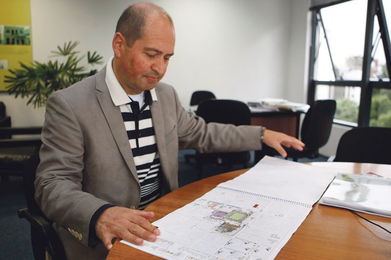 Reginaldo Cordeiro observa papelada da Arena. Acima, operário trabalha no estádio | Henry Milléo/ Gazeta do Povo