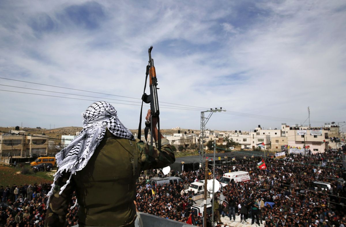 Homem armado e mascarado vigia o protesto feito durante um enterro do palestino Arafat Yaradat, morto em uma prisão israelense | Reuters/Darren Whiteside