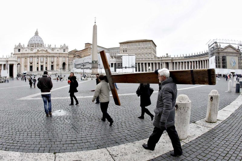 Peregrinos carregam uma cruz diante da Basílica de São Pedro, no Vaticano, no dia em que o Papa anunciou a sua saída | Reuters/ Giampiero Sposito