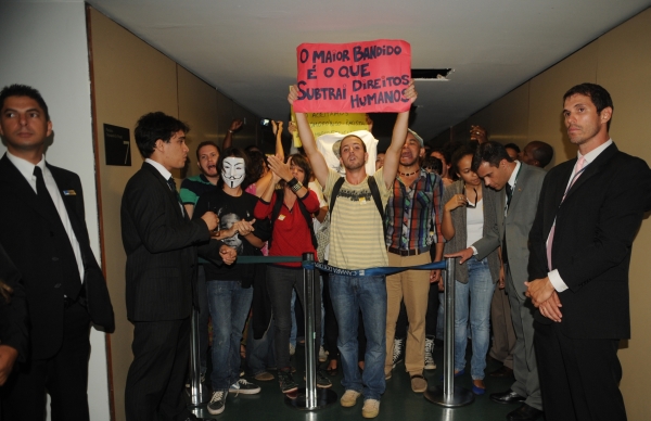 Pastor preside sessão por oito minutos: O deputado pastor Marco Feliciano permaneceu por apenas oito minutos presidindo a reunião da Comissão de Direitos Humanos na tarde de ontem. Apesar de a segurança da Casa ter barrado a entrada de alguns manifestantes, outros conseguiram burlar o bloqueio e fizeram protestos contra o deputado. A sessão discutiria os direitos humanos dos portadores de transtorno mental. Mas, depois de muito bate boca, após a saída do pastor, a reunião foi encerrada sem qualquer debate sobre o tema. O representante do ministério da Justiça, Aldo Zainden, abandonou o debate após iniciar o seu discurso afirmando que o país vive um retrocesso em relação aos direitos humanos. Ele diz ter sido censurado pelo deputado Jair Bolsonaro (PP-RJ), que o ordenou a falar apenas sobre o tema da audiência. Bolsonaro ainda bateu boca com manifestantes | Antônio Cruz/ABr