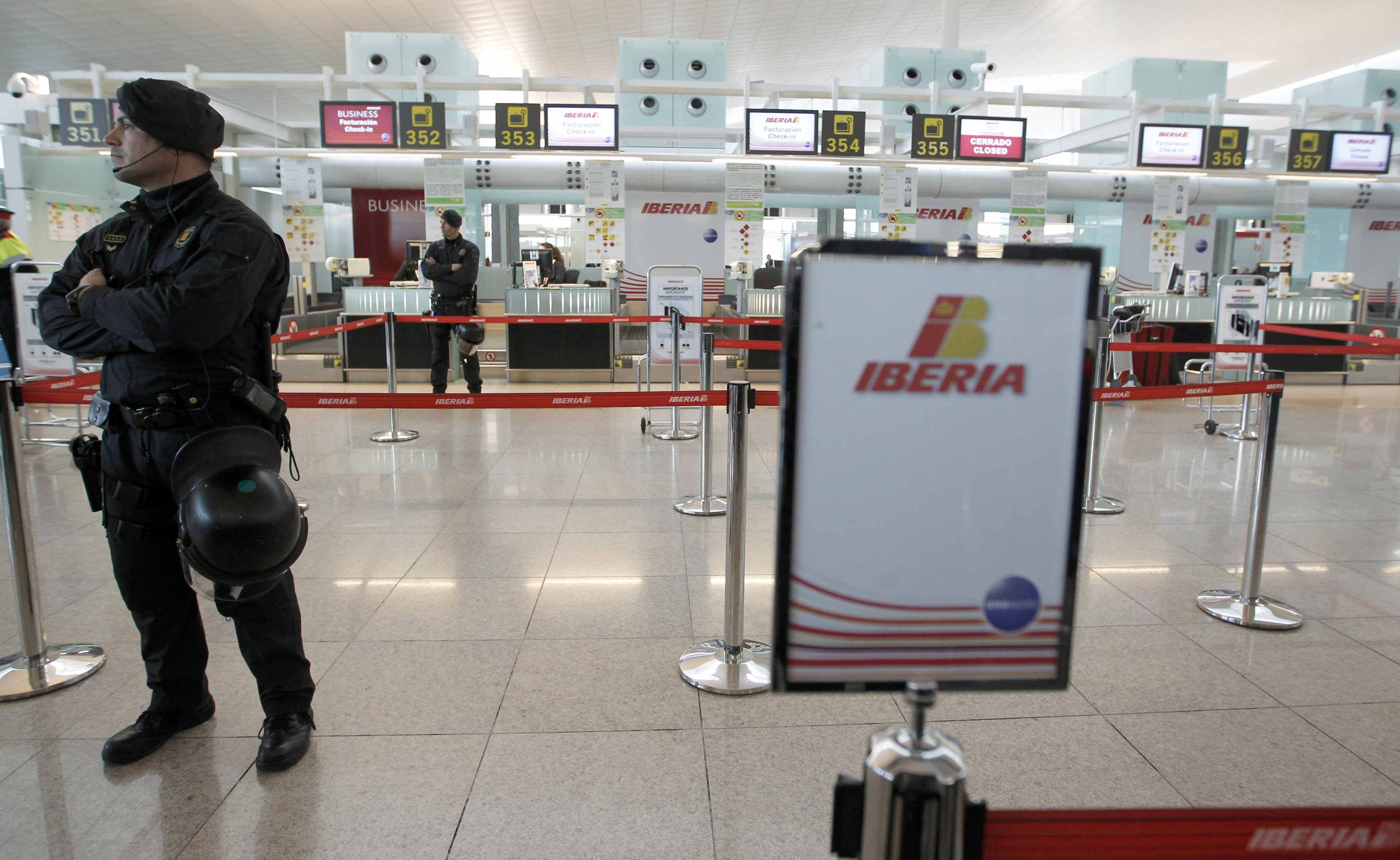 Policial faz guarda do balcão de check-in da Iberia no aeroporto de Barcelona, na Espanha | REUTERS/Albert Gea