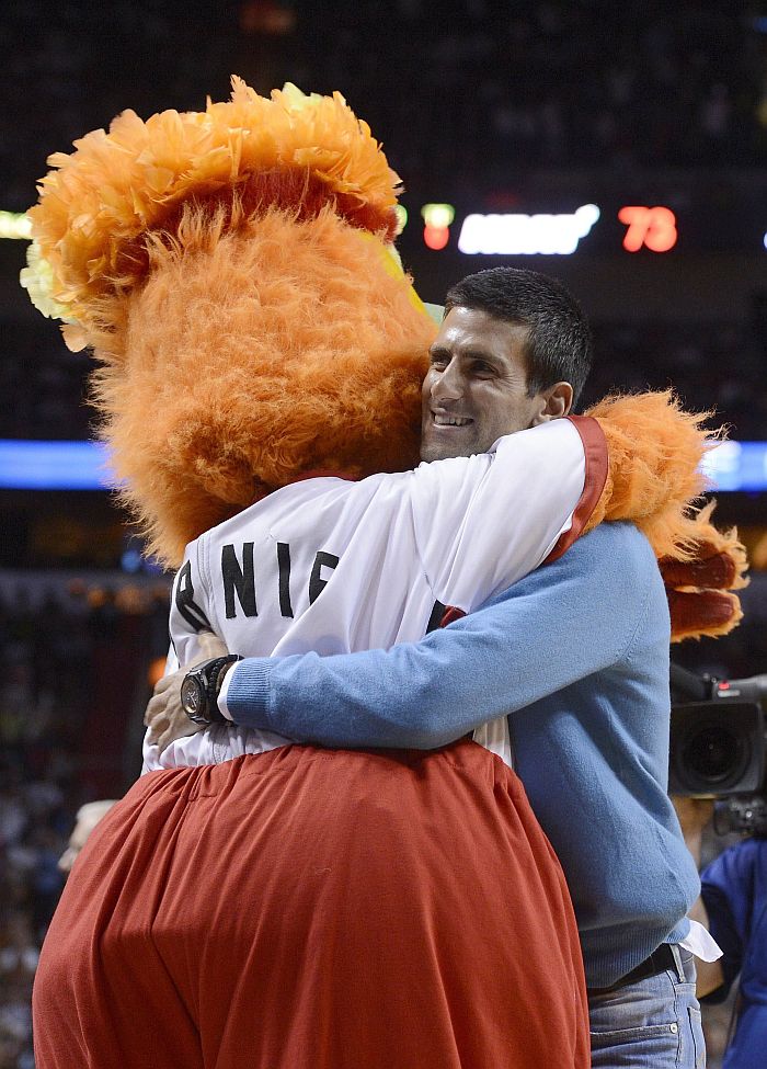 Tenista Novak Djokovic é abraçado pelo mascote do Miami Heat na vitória sobre o Charlotte Bobcats | EFE