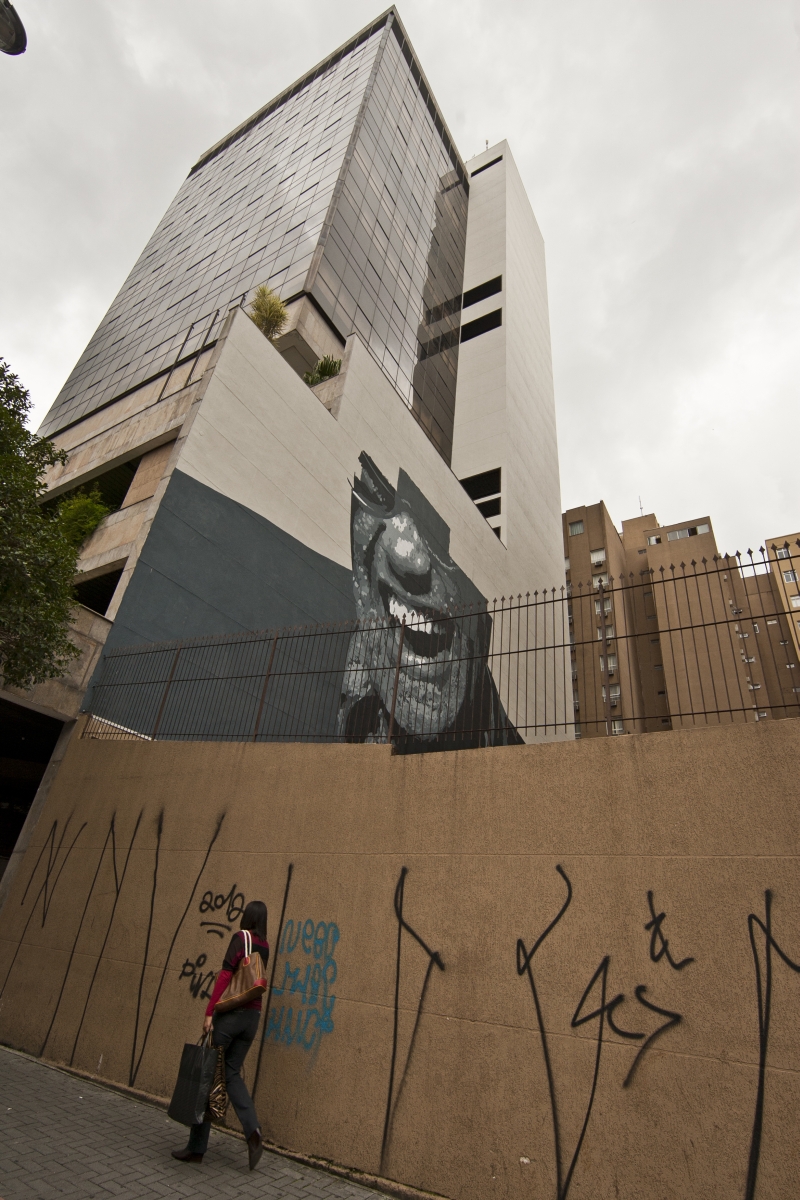 O rosto ainda incompleto do cantor Ray Charles divide a paisagem com pichações no muro: um agrada bem mais que o outro | Marcelo Andrade / Gazeta do Povo