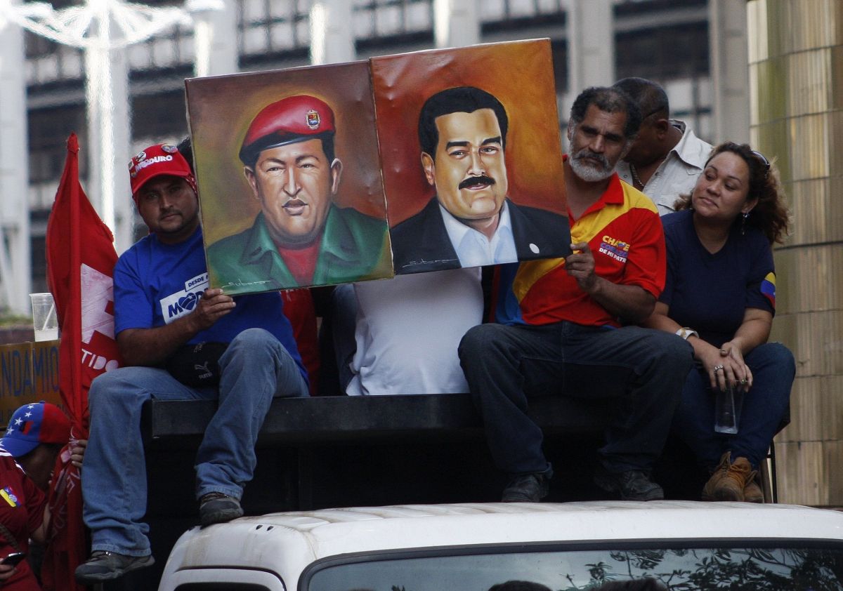 Simpatizantes de Maduro desfilam com um retrato do presidente eleito com o ex-líder venezuelano Hugo Chávez | Reuters/Marco Bello