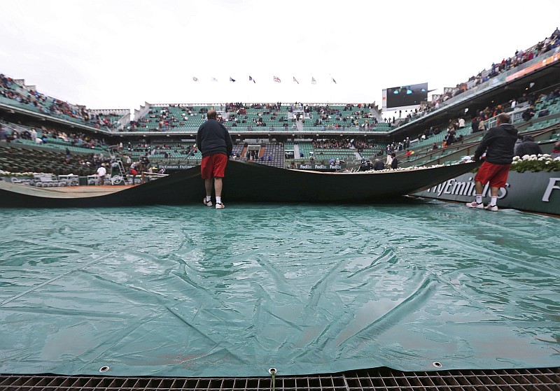 Operários cobrem com lonas o saibro de Roland Garros. Chuva interrompeu partidas pela segunda vez na semana | Stephane Mahe / Reuters
