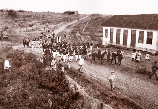 Préstito desfilando ao som da banda militar pela antiga Estrada do Portão, hoje Avenida República Argentina, a fim de participarem da inauguração da Sociedade Internacional da Água Verde no dia 1.º de janeiro de 1905. Ao fundo, o espaço da atual Praça do Japão | Acervo Cid Destefani