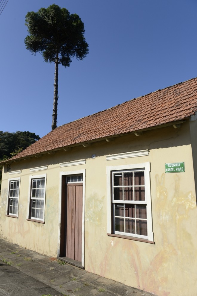 A fachada da casa amarelinha na Avenida Manoel Ribas, ao lado do parque Barigui e cercada pelo gramado verde, chama atenção |