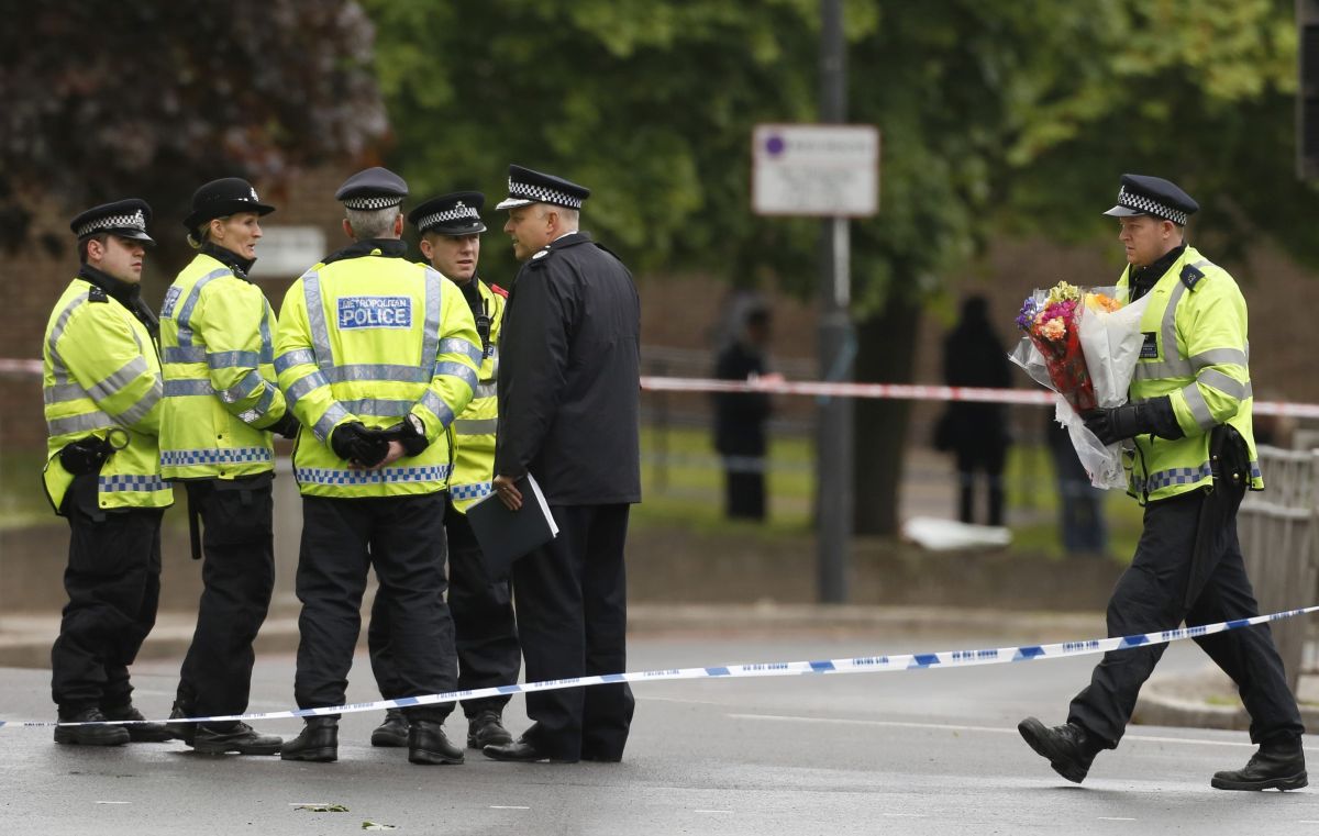 Policial leva flores ao local onde o soldado foi assassinado por supostos extremistas | Reuters/Luke MacGregor