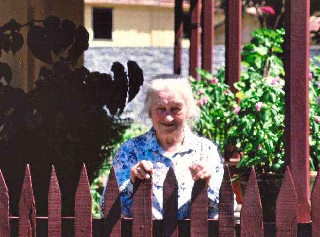 Nona Carolina Boscardin posa atrás da cerca de madeira |