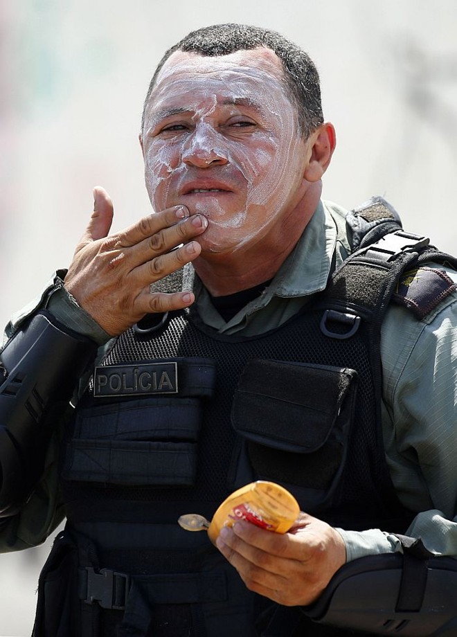 Policial do Batalhão de Choque se protege do sol no protesto em Fortaleza | 