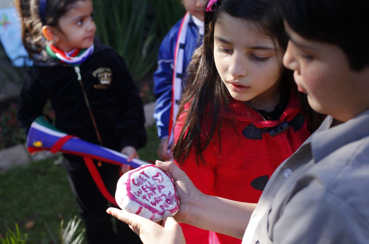 Crianças seguram uma pedra pintada com a mensagem de "melhore" para o ex-líder sul-africano Nelson Mandela | Reuters/Mike Hutchings