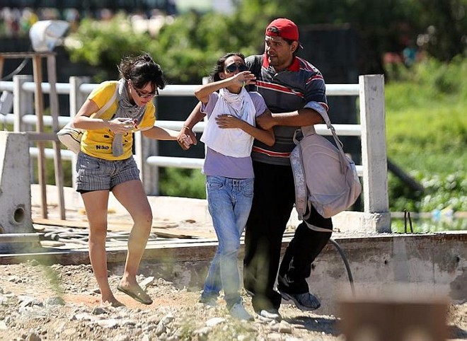 Manifestantes se protegem no confronto com a PM antes do jogo com o Brasil |