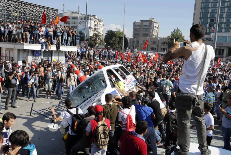 Manifestantes viram um carro de polícia durante protesto anti-governo na Praça Taksim, no centro de Istambul | REUTERS/Murad Sezer