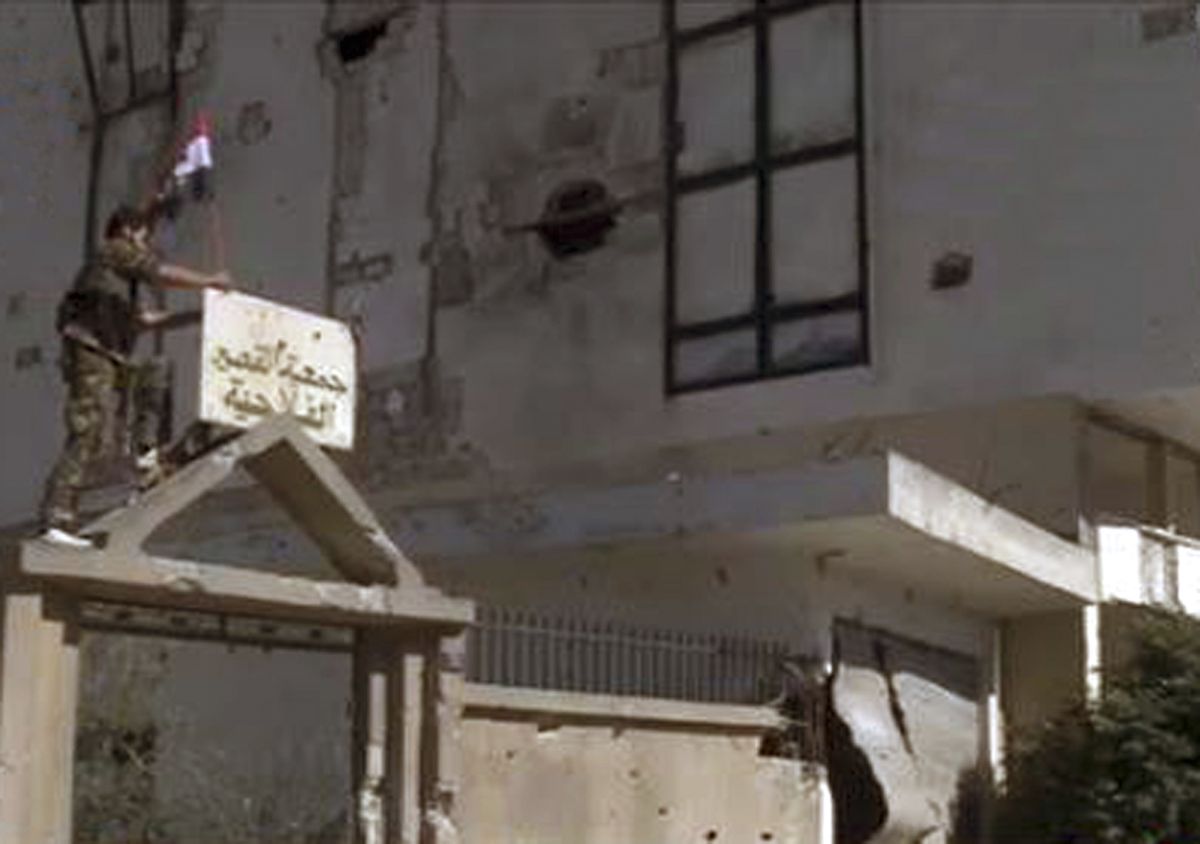 Soldado coloca uma bandeira do regime sírio no topo de um prédio em Al Qusair | Reuters/Sana/Divulgação