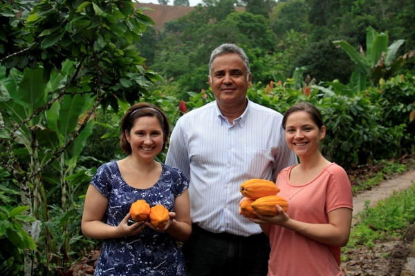 As irmãs Bibiana (à esq.) e Carolina Schneider, donas da Cuore Di Cacao, com o produtor baiano João Tavares, na região de Ilhéus. As duas foram tratar da ampliação da linha de chocolate fino Ouro Negro, produzido com cacau 100% brasileiro, lançada na última Páscoa | Cláudia Pereira/Divulgação