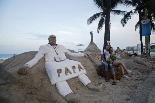 Jovens posam para foto ao lado de escultura do papa |