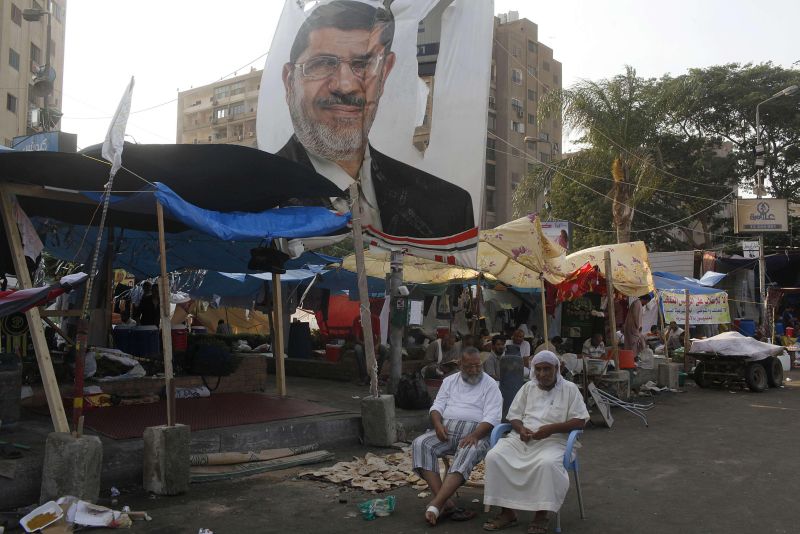 Apoiadores de Mursi descansam perto de um pôster rasgado do ex-presidente, perto da mesquita de Raba El-Adwyia, no Cairo | Asmaa Waghih/Reuters