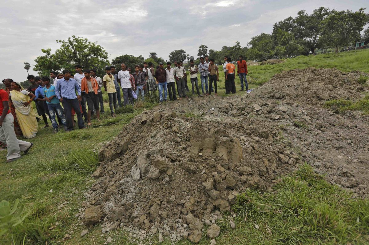 Familiares observam uma cova coletiva onde foram enterradas vítimas do envenenamento na Índia | Reuters/Adnan Abidi