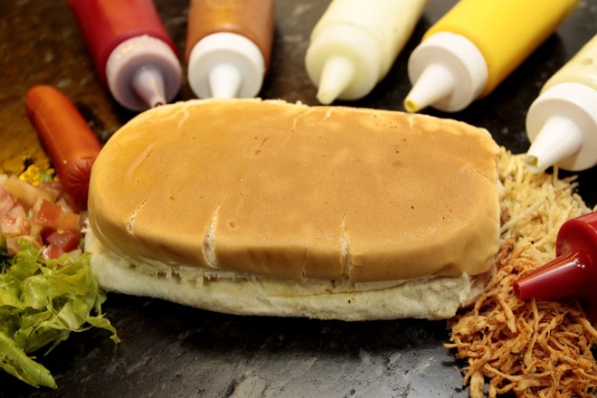 Cachorrão de frango prensado: versão leva salsicha, maionese, catchup, batata palha, tomate, alface e frango desfiado temperado com sazon e orégano. No Leonel Lanches | 