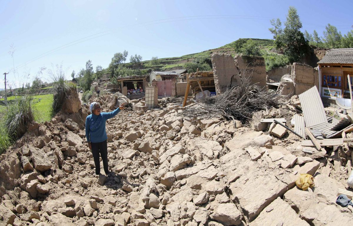 Mulher mostra a sua casa destruída pelo terremoto desta segunda-feira (22) no condado de Minxian | Reuters/Stringer