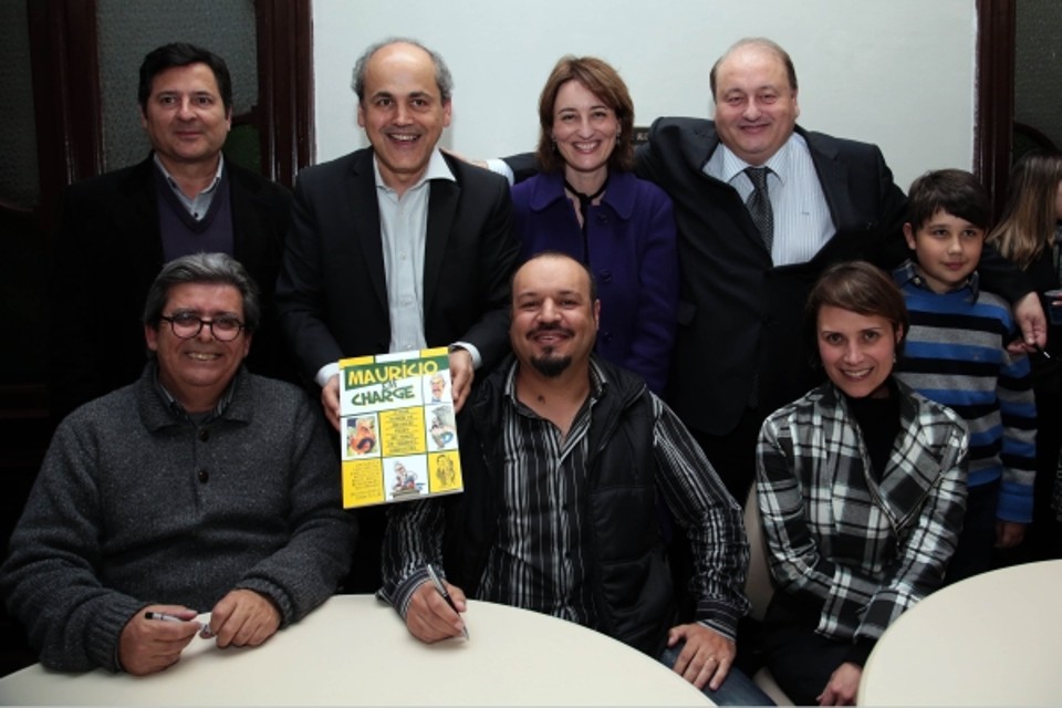 Filhos do ex-prefeito Maurício Fruet, Gustavo, Eleonora e Claudio Fruet, a nora Márcia Oleskovicz (à dir.) e Gabriel (filho de Eleonora) posam com alguns dos autores do livro Maurício em Charge, lançado ontem durante concorrida sessão de autógrafos no Salão Nobre da Faculdade de Direito da UFPR. Com eles na foto, o organizador do livro, Simon Taylor (de cavanhaque), Dante Mendonça (sentado, à esq.) e Rubens Gennaro (em pé, atrás) | Jaelson Lucas