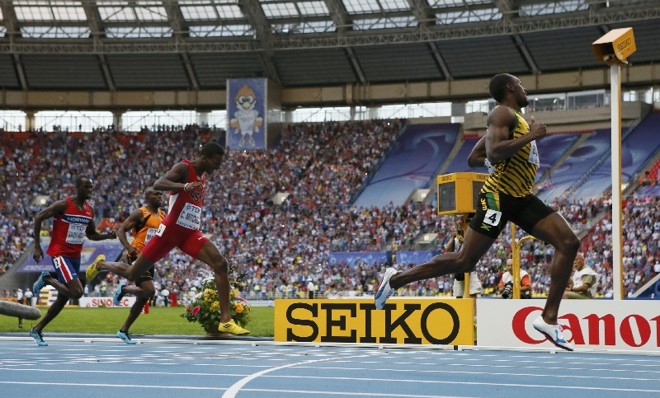 Tranquilo na dianteira, Bolt olha para a câmera ao lado da pista ao levar seu segundo ouro na Rússia | 