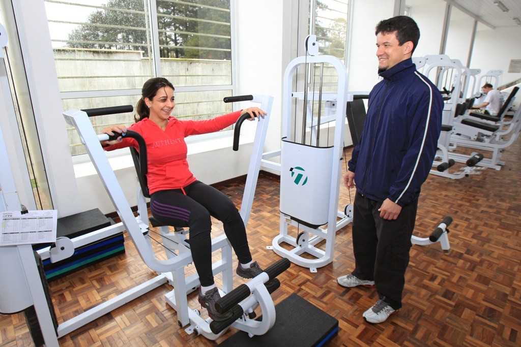O instrutor Otaviano Verissimo auxilia uma aluna na academia do Centro Politécnico.