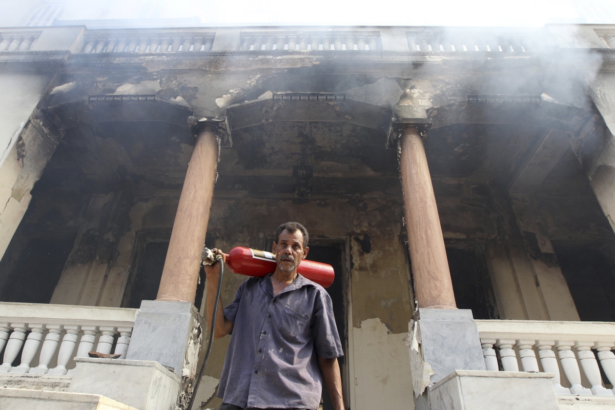 Homem sai com extintor de incêndio do prédio incendiado por manifestantes no Cairo | Reuters/Muhammad Hamed