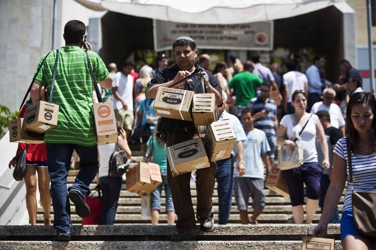 Homem carrega máscaras de gás após sair de um ponto de distribuição em Tel Aviv, Israel | Reuters/Nir Elias
