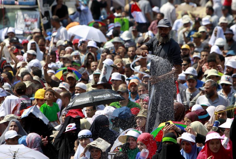 Contra o calor, homem espirra água em simpatizantes do ex-presidente Mohamed Mursi | Mohamed Abd El Ghany/Reuters