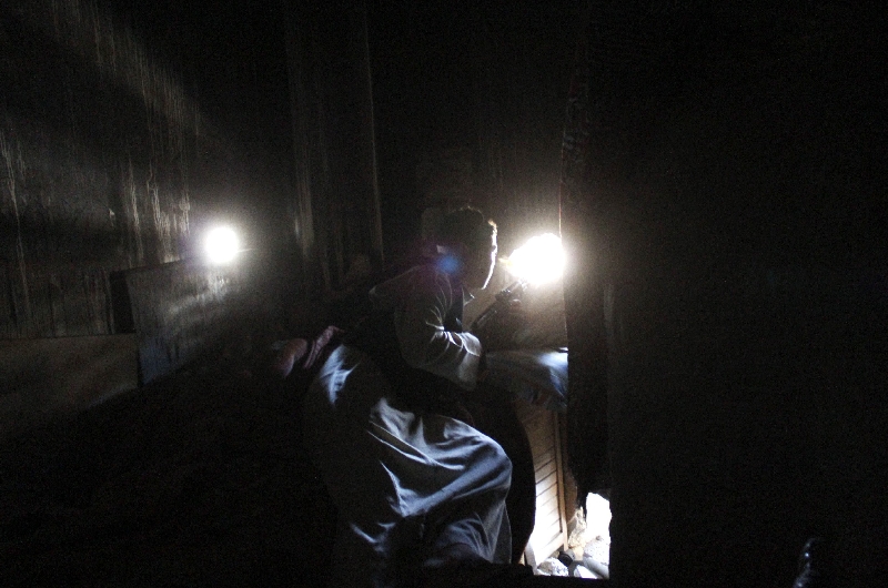 Soldado do Exército Livre da Síria espia as forças fiéis a Assad por um buraco na parede, em Aleppo | Molhem Barakat/Reuters