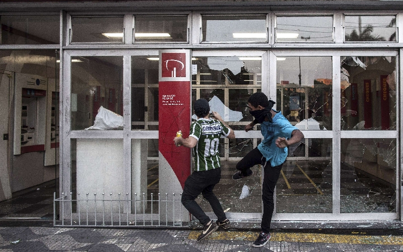 Mascarados quebram vidraças de agência bancária em São Paulo durante os protestos do dia Sete de Setembro: pichação de símbolo anarquista remete à origem do movimento Black Bloc, nos anos 80, na Alemanha | Victor Moriyama/Reuters