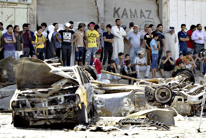 Pessoas observam carros destruídos por ataque em Basra | Essam Al-Sudani/Reuters