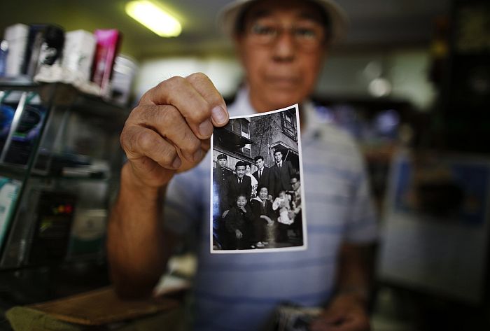 Kohei Jinno mostra fotos da família, que foi desalojada duas vezes para obras olímpicas | Issei Kato / Reuters