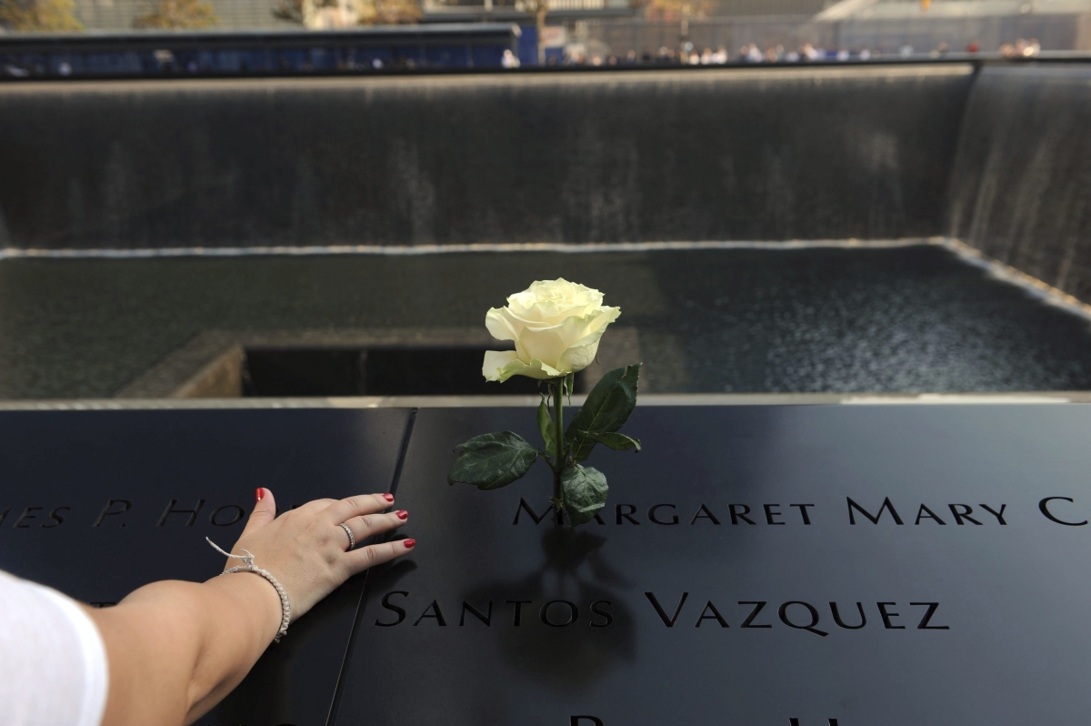 Mulher coloca uma flor sobre o nome de uma das vítimas do ataque | EFE/David Handschuh/Compartilhamento