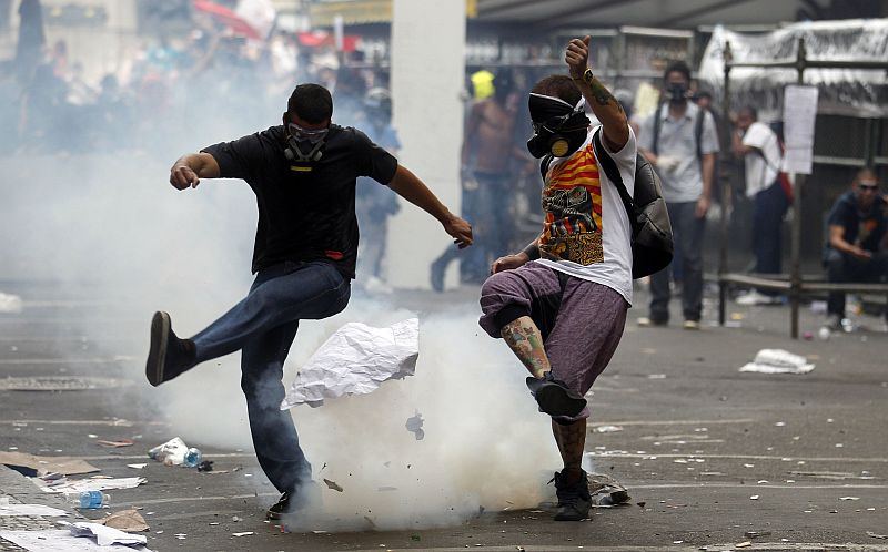 Manifestante chuta granada de gás diante da Câmara Municipal do Rio de Janeiro, durante confronto com policiais | REUTERS/Pilar Olivares