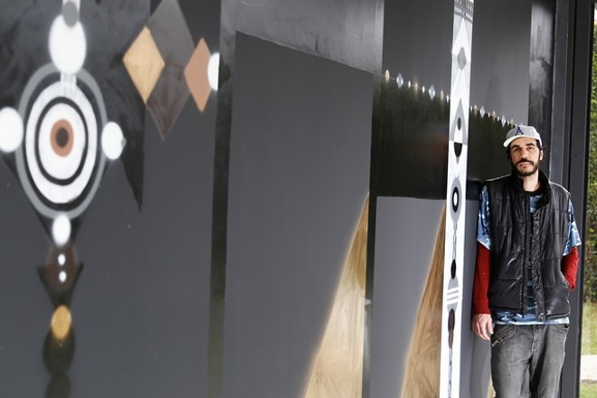 O artista goiano em frente ao painel em frente da SIM Galeria, que abre a sua exposição individual