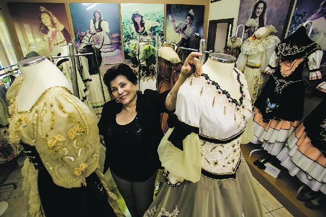 A historiadora Teresa Christensen entre os vestidos usados pelas rainhas da Fenasoja: tradição gaúcha. Foto: Marcelo Andrade/Gazeta do Povo |