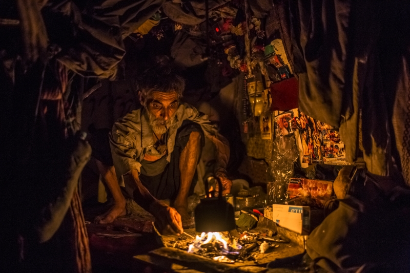 Adam Khan, de 45 anos, deixou a família para fumar heroína em um abrigo cavernoso de pedra | Daniel Berehulak Para The New York Times