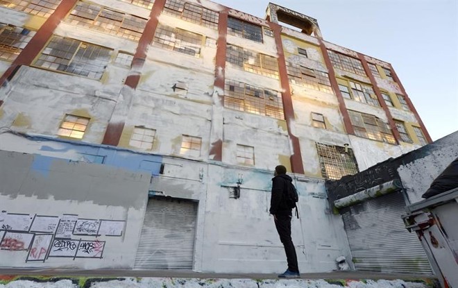 Homem observa a fachada do prédio 5 Pointz já com tinta branca sobre os grafites | 