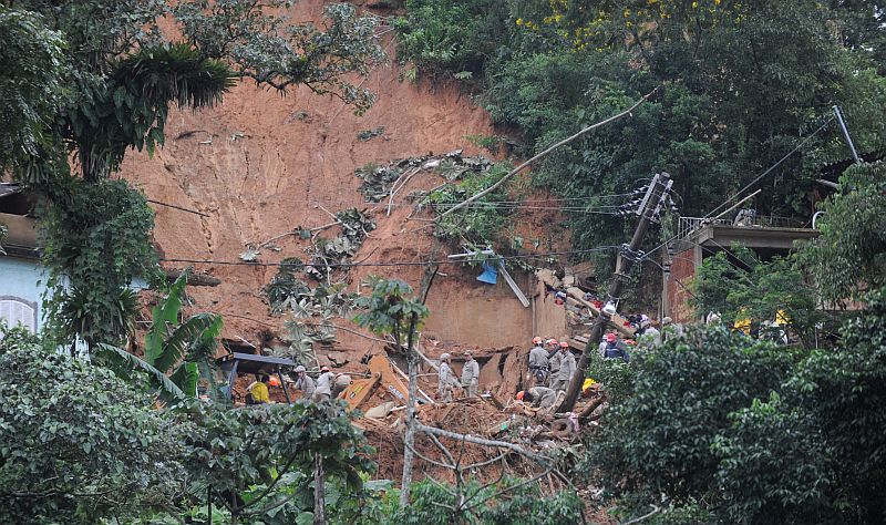 Homens tentam escapar da lama em rua de Bonsucesso, na capital fluminense: chuvas provocaram estragos e mortes no estado do Rio | Agência Brasil / Foto repórter Cristina Índio