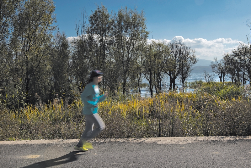 Poluição, trânsito e o estresse da vida na cidade estão atraindo chineses das áreas urbanas para as rurais. Lin Liya, de 34 anos, que se mudou de Xangai para Dali, corre na margem do lago Erhai | Gilles Sabrie para The New York Times
