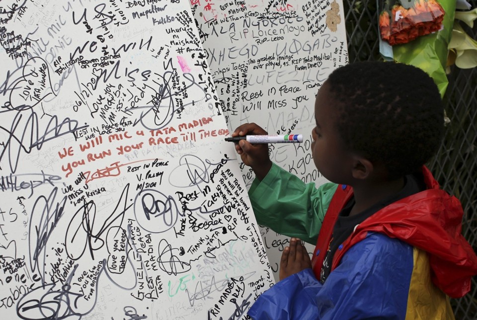 Menino presta sua homenagem em frente à casa do líder sul-africano Nelson Mandela, morto na quinta-feira (5) | Reuters/Siphiwe Sibeko