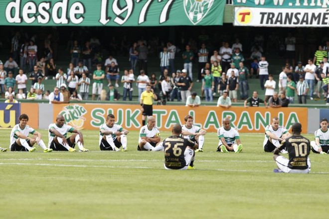 Jogadores sentados no gramado antes do início do jogo |