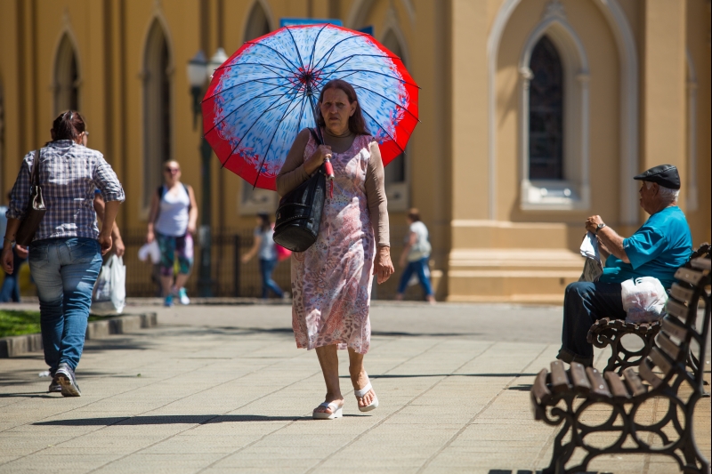 Por causa do Sol forte, o guarda-chuva fez as vezes de guarda-sol | Brunno Covello/Agência de Notícias Gazeta do Povo