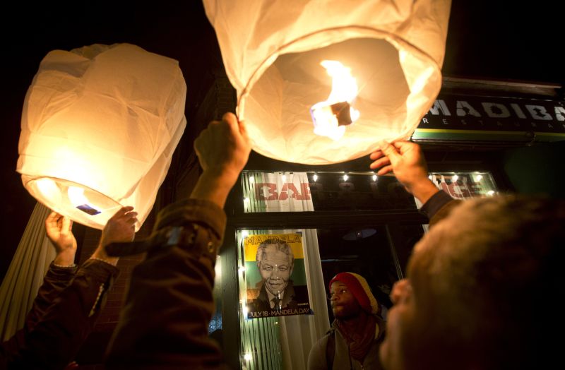 Agitando bandeiras, com câmeras, flores, canções e bailes, centenas de pessoas de diferentes raças e religiões homenageiam o grande herói sul-africano | REUTERS/Carlo Allegri