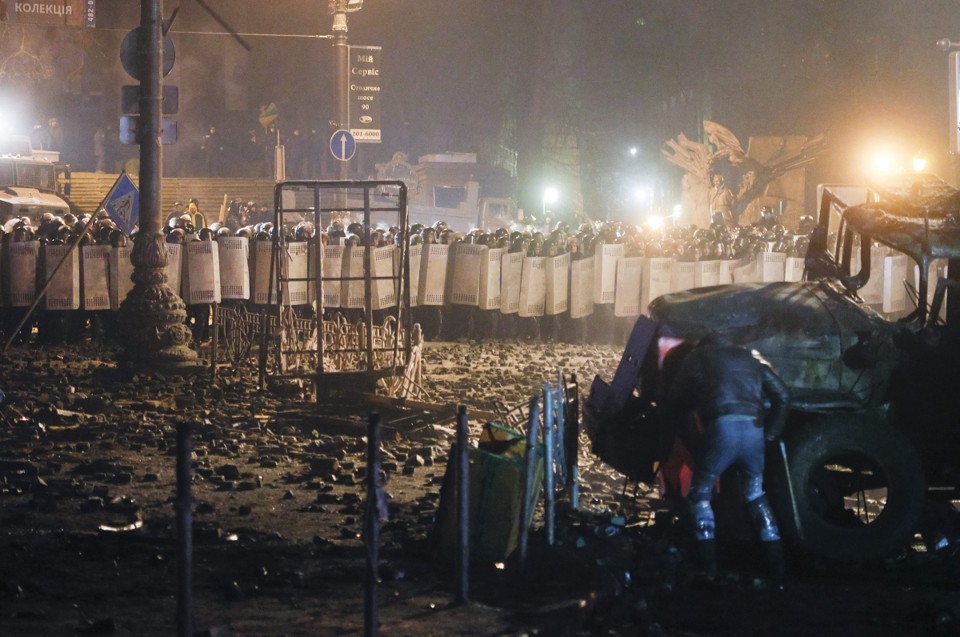 Manifestante usa veículo queimado como barricada em confronto com os policiais em Kiev | EFE/Sergey Dolzhenko